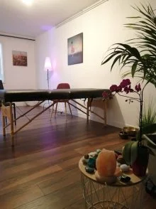 La salle de soins du cabinet : table de soin, orchidée, plantes vertes et pierres sur un guéridon, lumière douce