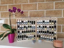Coffrets ouverts de flacons d’huiles essentielles devant un mur en pierre, à côté d’une orchidée en pot rose