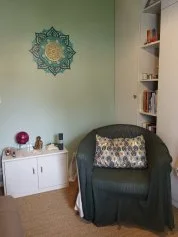 Le petit salon : fauteuil, mandala au mur, petit meuble et bibliothèque